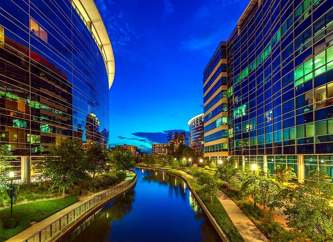 The Woodlands, TX - Closeup View of Brightly Lit Commercial Buildings Next to a River at Night in The Woodlands Texas